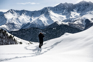 Fototapeta na wymiar photographer in a black jacket against the background of mountains and gorges against the background of snow
