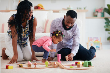 happy family with toddler baby playing wooden railway together at home