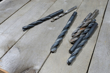 many old drills lie on a plank wooden background. close-up.