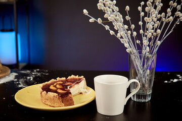 Piece of homemade cake with fruits on the orange plate with flowers and cup. Morning in studio