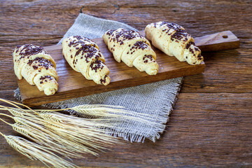 Delicious frozen belgian croissants ready to bake with spikelets on wooden background
