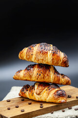 Croissants on a wooden board and a black wooden table. Free space for text. Vertical image