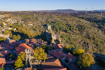 Drone aerial panorama of historic village of Sortelha with castle and with turbines on natural landscape, in Portugal © Luis