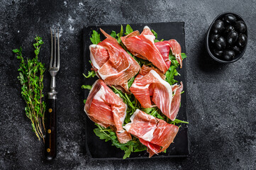 Sliced Jamon serrano pork ham meat on a marble board. Black background. Top view - obrazy, fototapety, plakaty