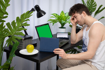 The employee worries about the next meeting in order to conduct the conversation well. A domain computer workstation among potted plants with bright lighting. Green screen of monitor ready to design.