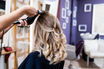 Fototapeta premium Beautiful hairstyle of young adult woman after dyeing hair and making highlights in hair salon.