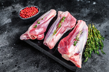 Raw lamb shanks meat on a marble board. Black background. Top view