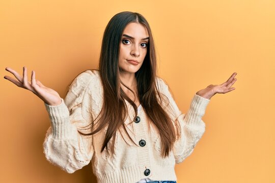 Beautiful brunette young woman wearing casual clothes clueless and confused with open arms, no idea and doubtful face.
