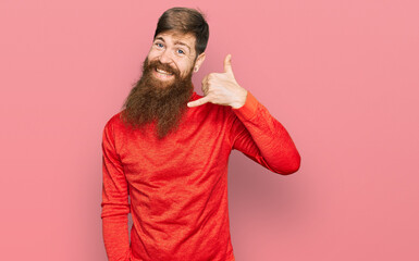 Redhead man with long beard wearing casual clothes smiling doing phone gesture with hand and fingers like talking on the telephone. communicating concepts.