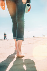 Voyage à la plage - femme dans un jeanse marchant sur la plage de sable laissant des empreintes de pas dans le sable. Gros plan détail des pieds féminins et du sable sur la côte hollandaise, mer du Nord