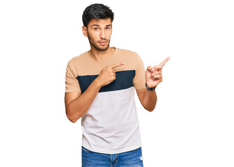 Young handsome man wearing casual clothes pointing aside worried and nervous with both hands,...