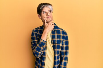 Young hispanic man wearing casual clothes thinking concentrated about doubt with finger on chin and looking up wondering