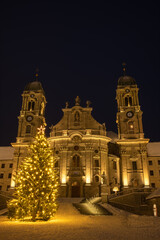 Illuminated swiss abbey of Einsiedeln in snowy Christmas time and winter night