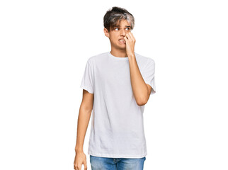 Young hispanic man wearing casual white tshirt looking stressed and nervous with hands on mouth biting nails. anxiety problem.