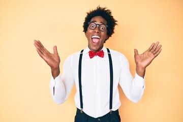 Handsome african american man with afro hair wearing hipster elegant look celebrating crazy and...