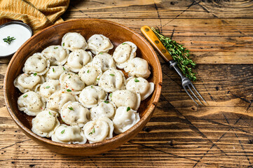 Homemade Russian Dumplings Pelmeni with beef and pork meat in a wooden bowl. wooden background. top view. Copy space