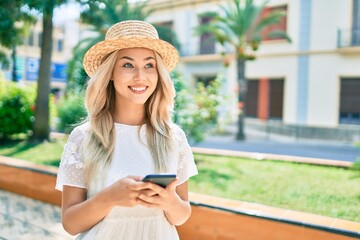 Young caucasian tourist girl smiling happy using smartphone at street of city.