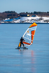 An alone surfer ice surfing on the frosen sea on a sunny spring day.