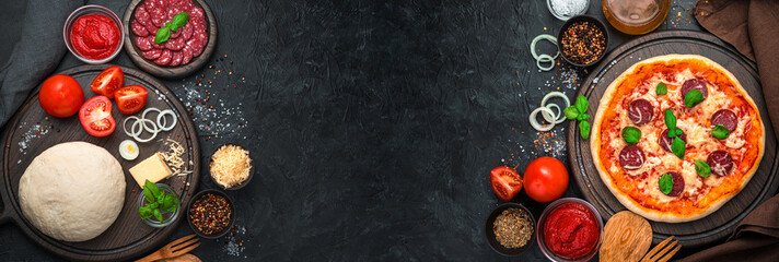 Raw ingredients and ready-made pizza on a black background.
