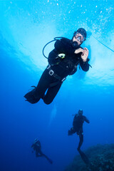 Naklejka na ściany i meble Group of divers swim over koral reef. 