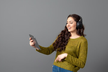 Naklejka premium young woman with headset and tablet in hand playing games and talking to friends online