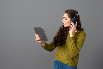 young woman with headset and tablet in hand playing games and talking to friends online