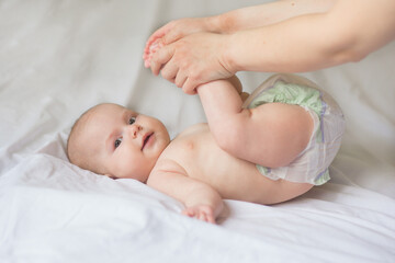 Happy infant girl doing baby massage by his mother at home. Newborn child about 5 months old