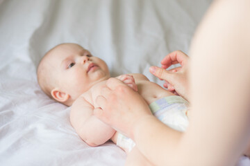 Happy infant girl doing baby massage by his mother at home. Newborn child about 5 months old