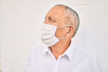 Senior man wearing medical mask standing at the city.