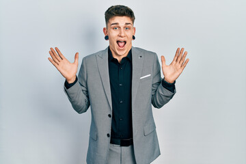 Young caucasian boy with ears dilation wearing business jacket celebrating crazy and amazed for success with arms raised and open eyes screaming excited. winner concept