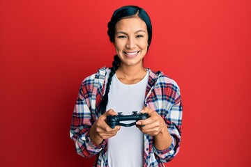 Beautiful hispanic woman playing video game holding controller smiling with a happy and cool smile on face. showing teeth. © Krakenimages.com