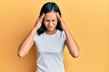 Beautiful hispanic woman wearing casual white tshirt with hand on head for pain in head because...