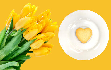 Biscuits-heart on a white plate and yellow tulips on a yellow background