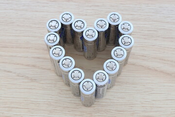 Heart made of AA batteries. On wooden background, closeup. Lithium batteries heart.