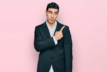 Handsome hispanic man wearing business clothes pointing with hand finger to the side showing advertisement, serious and calm face