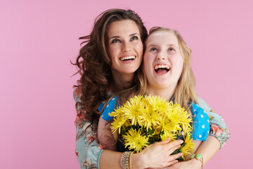 smiling trendy mother and daughter hugging on pink
