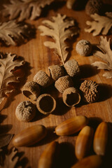 Autumnal background. Oak leaves and acorns on wooden background. 	