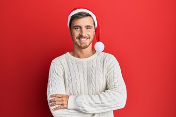 Handsome caucasian man wearing christmas hat happy face smiling with crossed arms looking at the camera. positive person.