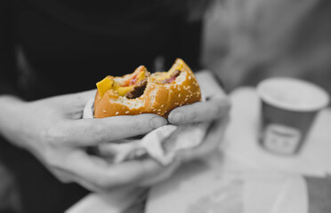 Woman holding hamburger in fast food restaurant.