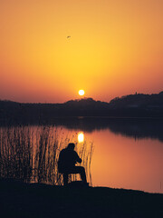 Fisherman on the shore of a lake at sunset