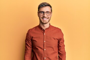 Handsome caucasian man wearing casual clothes and glasses with a happy and cool smile on face....