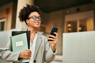 Young african american businesswoman smiling happy using smartphone at the city.