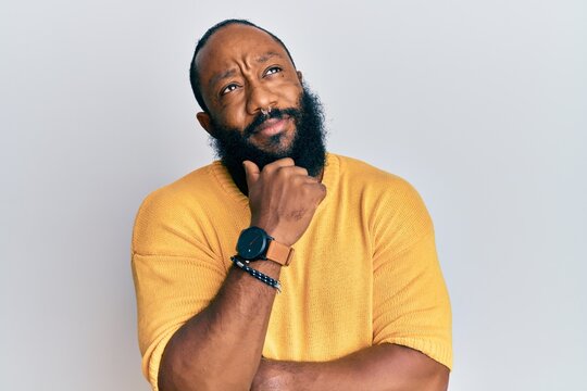 Young african american man wearing casual clothes thinking concentrated about doubt with finger on chin and looking up wondering