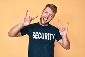 Fototapeta premium Young caucasian man wearing security t shirt shouting with crazy expression doing rock symbol with hands up. music star. heavy concept.