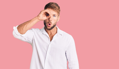 Young caucasian man wearing casual clothes doing ok gesture shocked with surprised face, eye looking through fingers. unbelieving expression.