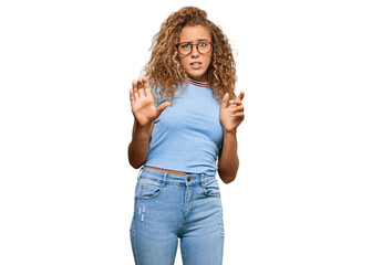 Beautiful caucasian teenager girl wearing casual clothes and glasses disgusted expression, displeased and fearful doing disgust face because aversion reaction. with hands raised