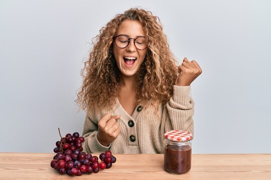 Beautiful caucasian teenager girl making grape jam celebrating surprised and amazed for success with arms raised and eyes closed
