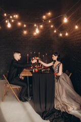 Wedding of a beautiful couple in a black dress, a bouquet of marsala color, at a festive table with...