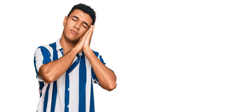 Young arab man wearing casual clothes sleeping tired dreaming and posing with hands together while smiling with closed eyes.