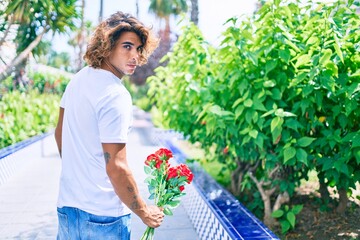 Young hispanic man holding bouquet of roses. Standing with unhappy expression for break up relationship.